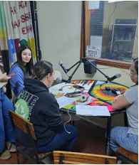 Fotografía del programa radial. 4 estudiantes frente a los micrófonos