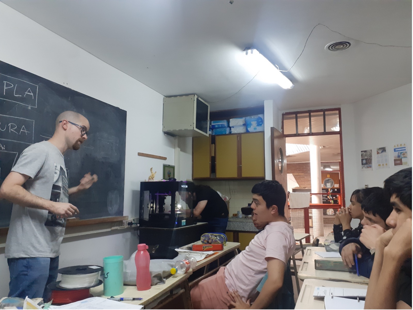 Fotografía en un aula. Docente explicando y estudiantes prestando atención