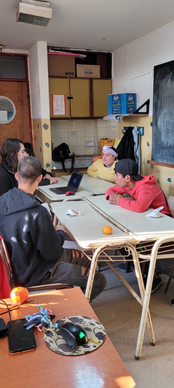 Fotografía en un aula. Estudiantes con una computadora