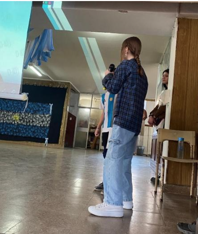 Fotografía del acto. Dos estudiantes exponiendo con micrófono