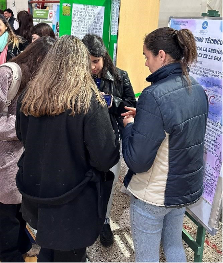 3 personas dialogando entre ellas, junto a un poster
