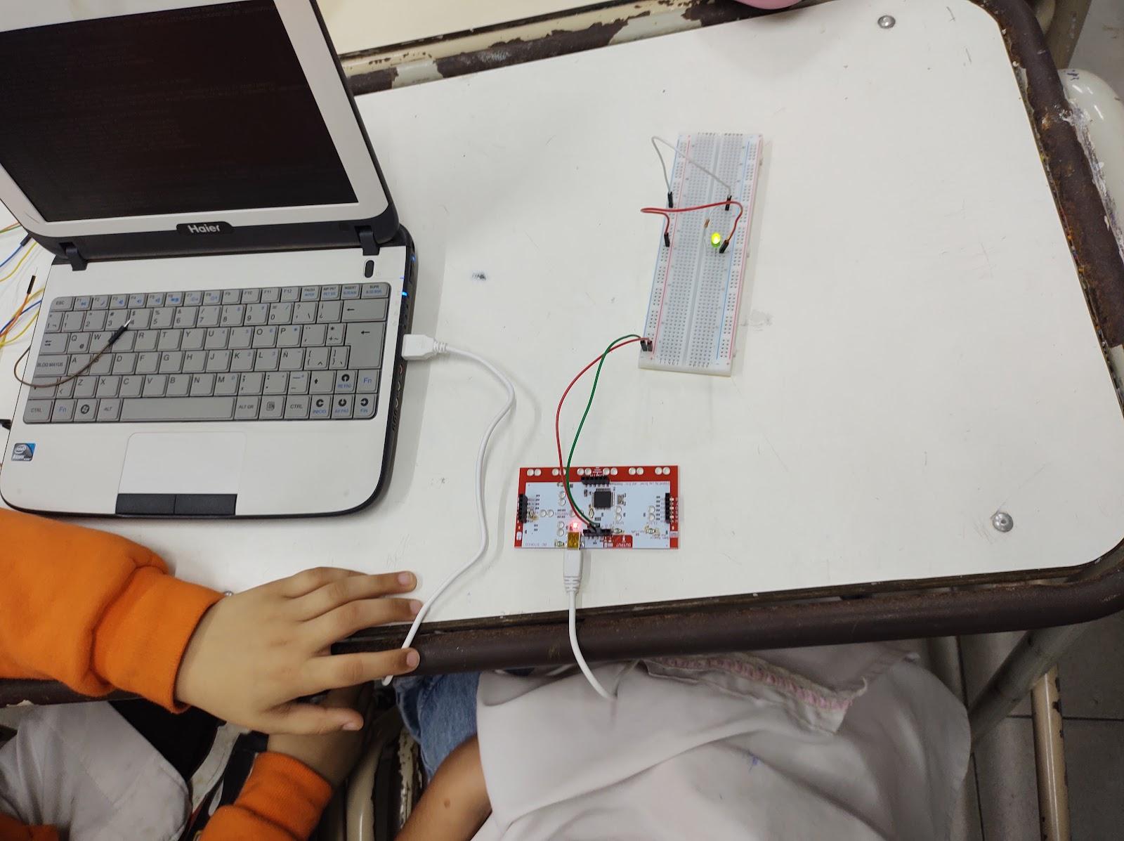 Fotografía de una computadora con un cable USB conectado a una placa y esa esta conectada a otra.