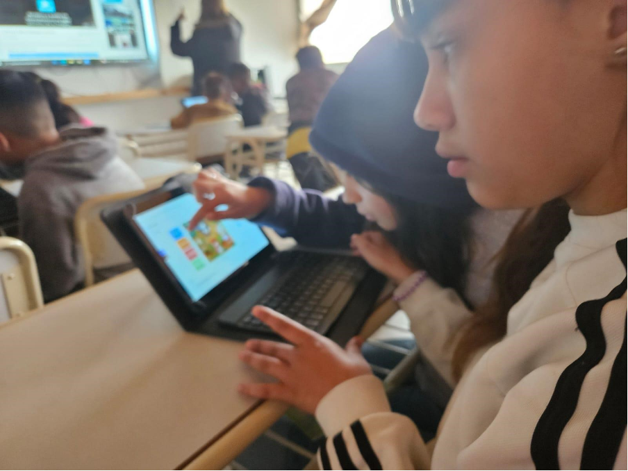 Dos estudiantes trabajando muy concentrados con una computadora en la mesa de un aula