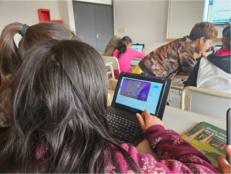 Dos estudiantes trabajando muy concentrados con una computadora en la mesa de un aula
